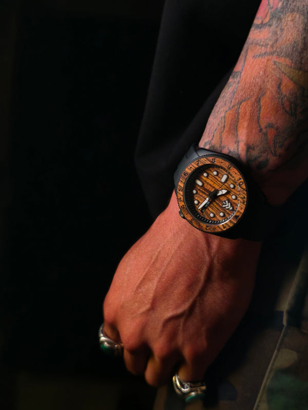 Hand wearing a wooden watch with intricate design on a dark background